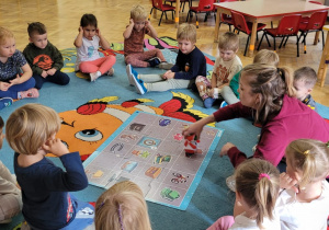 Prowadząca prezentuje matę i robota maluchom siedzącym w kole.