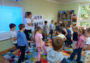 Dzieci wykonują zadanie ruchowe - naśladują kopanie piłki.