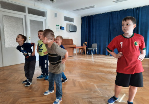 Pięciu chłopców stoi z rękami na bioderkach.