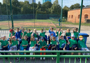 Grupa starszaków siedzi na trybunach stadionu.