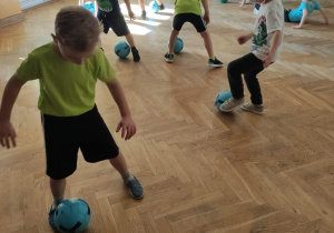 Dzieci bawią się piłką kopiąć raz do prawej nogi, raz do lewej.