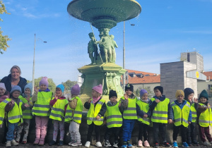 Grupa maluszków stoi przy fontannie.