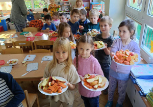 Dzieci z pokrojonymi jabłkami i marchewkami podchodzą do sokowirówki.