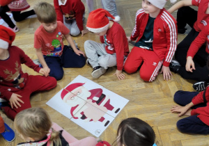 Starszaki siedzą wokół ułożonej w grupie mikołajkowej układanki.