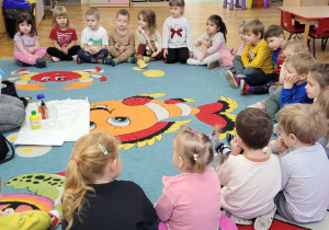 Maluchy obserwują jak prowadząca wlewa wodę do pojemnika.