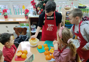 Projekt "Wiem, co jem": Chłopiec wyciska sok z połowy pomarańczy.