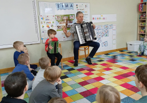 Bohater tygodnia: Chłopiec wraz z dziadkiem siedzą na krzesełkach i prezentują instrumenty.