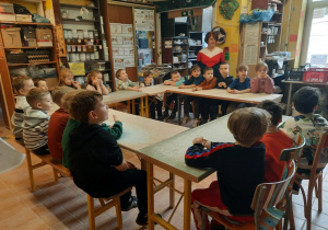 Starszaki siedzą przy stołach w pracowni ceramicznej.