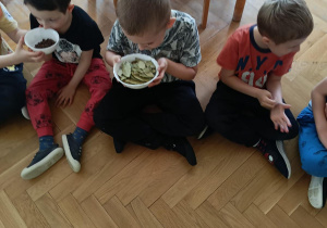 Dwaj chłopcy trzymają w dłoniach miseczki z ziołami i poznają ich zapach.