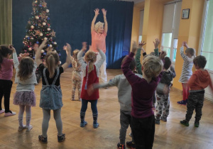 Dzieci tańczą razem z panią instruktor, powtarzają kroki za nią.