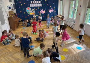 Przedszkolaki na pauzę w muzyce dotykają koła w wymienionym przez nauczycielkę kolorze podaną przez nią częścią ciała.