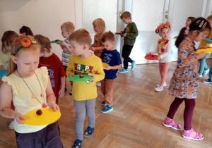 Przedszkolaki chodzą po sali trzymając kasztanka na krążku gimnastycznym.