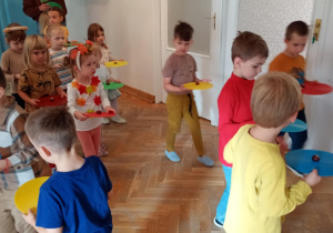 Przedszkolaki chodzą po sali trzymając kasztanka na krążku gimnastycznym.