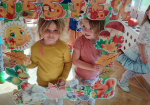 Dwie dziewczynki pozują wewnątrz jesiennej fotobudki.