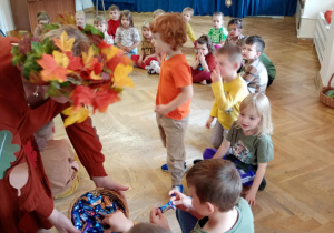 Pani Jesień częstuje dzieci cukierkami na koniec wspólnej zabawy.