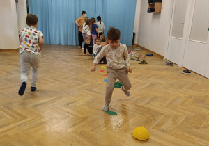 Dzieci stoją w pociągu, a jeden chłopiec przeskakuje z podeściku na podeścik.