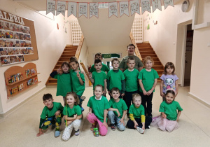 Starszaki ubrane w zielone koszulki pozują pod girlandą z napisem Dzień Sportu.