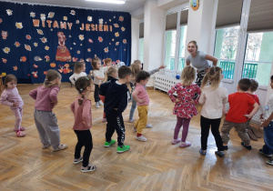 Przedszkolaki trzymając ręce na bioderkach poruszają nimi dookoła.