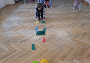 Chłopiec kładzie ręce na podkładki sensoryczne w kształcie rąk.