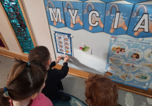 Chłopiec przyczepia do tablicy wybrany przez siebie środek do mycia - szczoteczkę elektryczną.