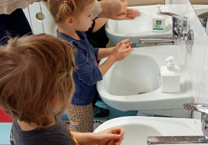 Nauczycielka prezentuje dzieciom jak dokładnie umyć część dłoni w pobliżu kciuka.