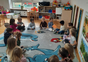 Przedszkolaki siedzą w kole i podają sobie kopertę otrzymaną od zaprzyjaźnionego przedszkola z Krakowa.