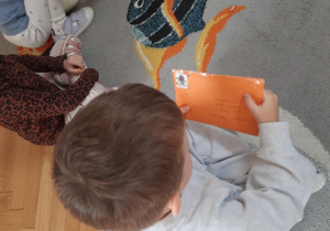 Chłopiec trzyma w ręku kopertę i ją ogląda.