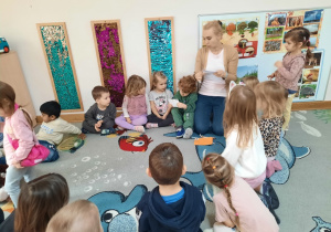 Chłopiec ogląda pocztówkę z Krakowa, a Nauczycielka odczytuje dzieciom list.