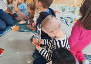 Chłopiec trzyma w ręku i ogląda pocztówkę z Krakowa.