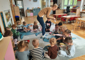 Nauczycielka rozdaje dzieciom naklejki ze zwierzątkami, prezent od dzieci z grupy Pantery.