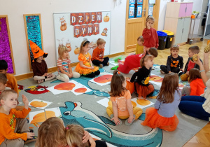 Nauczycielka pokazuje dzieciom ozdobne dynie i wspólnie przeliczają ich ilość.