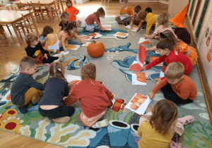 Przedszkolaki w parach układają dyniowe puzzle.