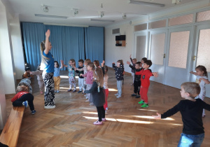 Dzieci wyciągają ręce do góry.