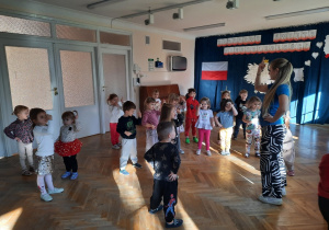 Maluchy stoją w rozsypce i wskazują paluszkiem do góry.