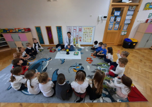 Maluchy siedzą w dużym półkolu, na środku rozłożona jest cerata z modelem Układu Słonecznego.