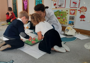 Chłopiec z dziewczynką odbijają foremki w zielonym piasku kinetycznym.