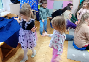 Chłopczyk i dwie dziewczynki szukają serduszek ukrytych w sali.