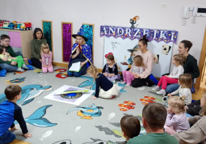 Dziewczynka siedzi na środku dywanu i kręci Kołem Fortuny.