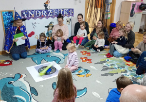 Dziewczynka siedzi na środku dywanu i kręci Kołem Fortuny.