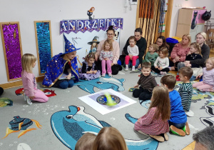 Chłopiec siedzi na środku dywanu i kręci Kołem Fortuny.