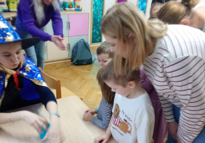 Chłopiec przygląda się jak nauczycielka przestawia kubeczki.