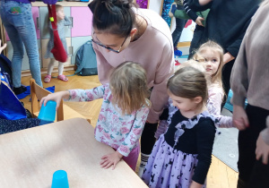 Dziewczynka podnosi wybrany kubeczek.