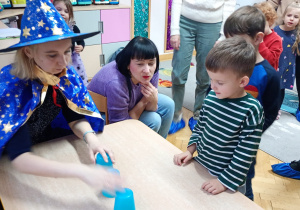 Chłopiec przygląda się jak nauczycielka przestawia kubeczki.