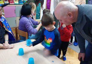 Chłopiec podnosi wybrany kubeczek.