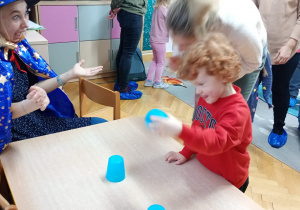 Chłopiec podnosi wybrany kubeczek.