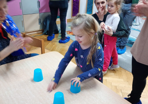 Dziewczynka podnosi wybrany kubeczek.