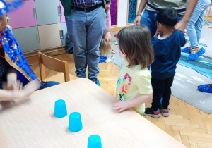 Dziewczynka zastanawia się, który kubeczek wybrać.