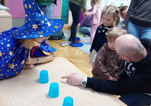 Dziewczynka z pomocą taty wybiera jeden z kubeczków.