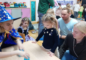 Dziewczynka przygląda się jak nauczycielka przestawia kubeczki.