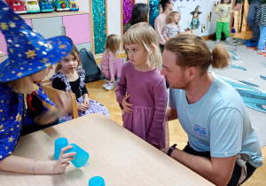 Nauczycielka podnosi wybrany przez dziewczynkę kubeczek do góry.